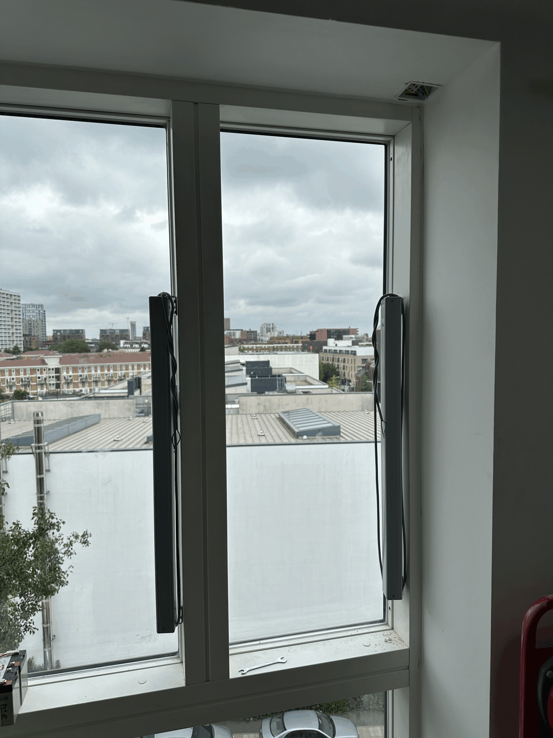Heavy-duty vertical electric window actuators fitted to tall commercial windows for precise climate control and automatic opening.