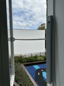 lose-up detail of an SE Controls electric chain actuator fully extended to automate window opening for fresh air ventilation.