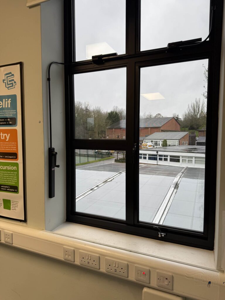 Close-up of a black Clearline Midi manual window winding system mounted on a white wall.