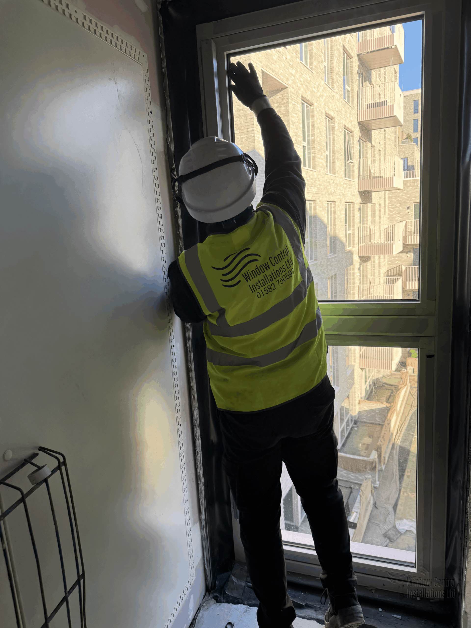 Window Controls Installations engineer working at height to install an AOV electric actuator on a commercial window providing smoke ventilation. 