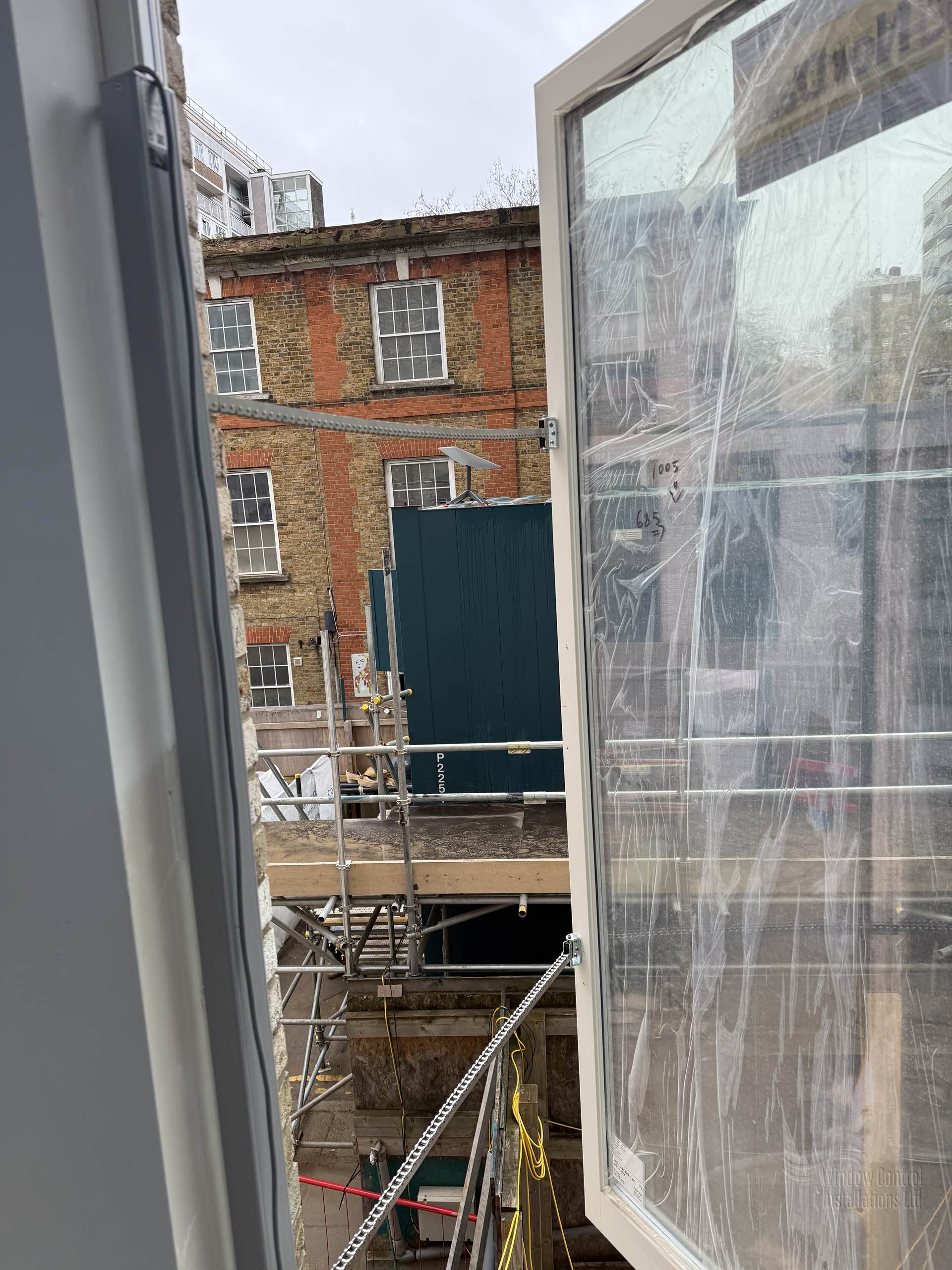 Smoke ventilation window installation in progress on a refurbishment project, looking out towards existing red brick buildings.