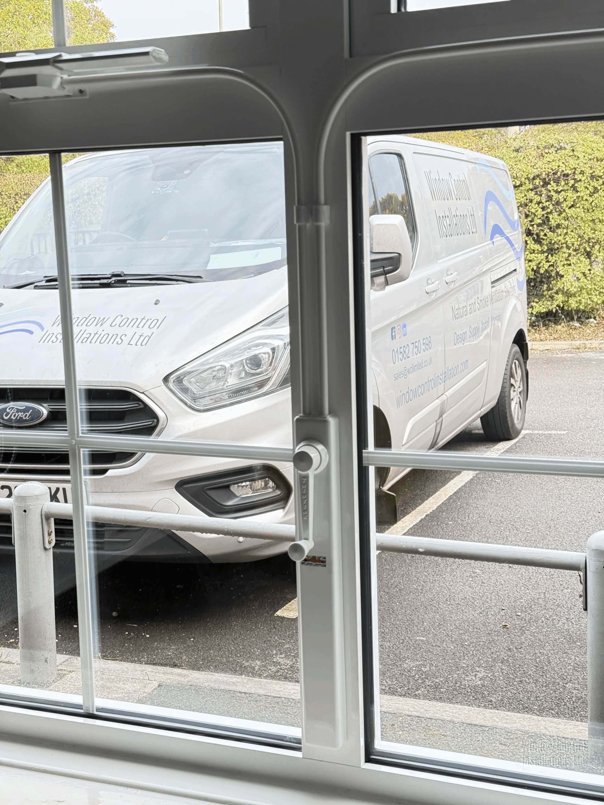Manual Window Controls installed on a white window frame, with a Windows Control service van in the background.